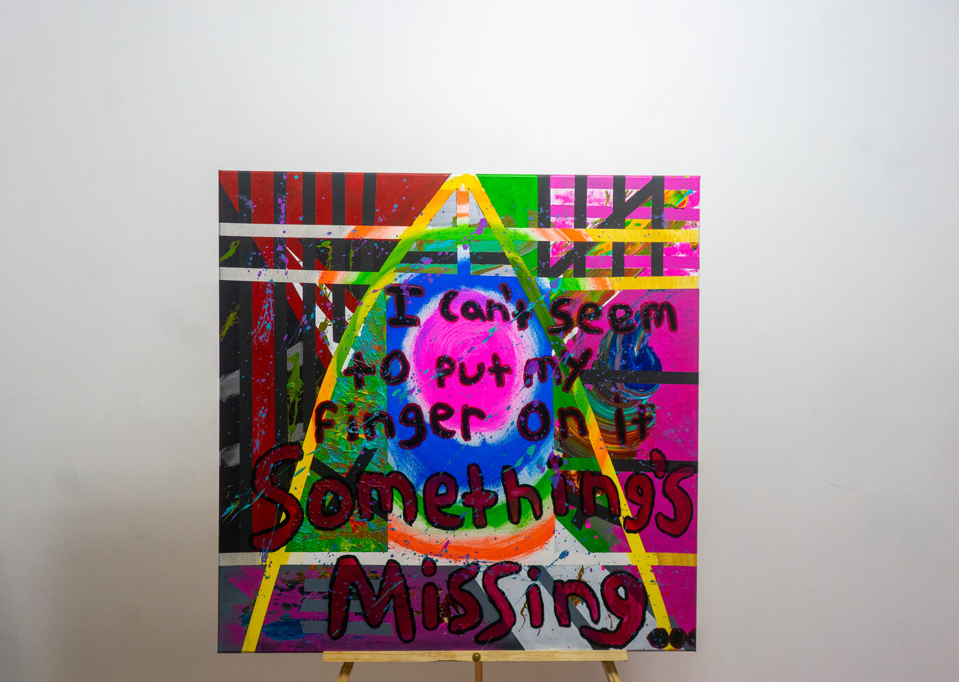 Painting reading Something's missing over a colorful geometric background