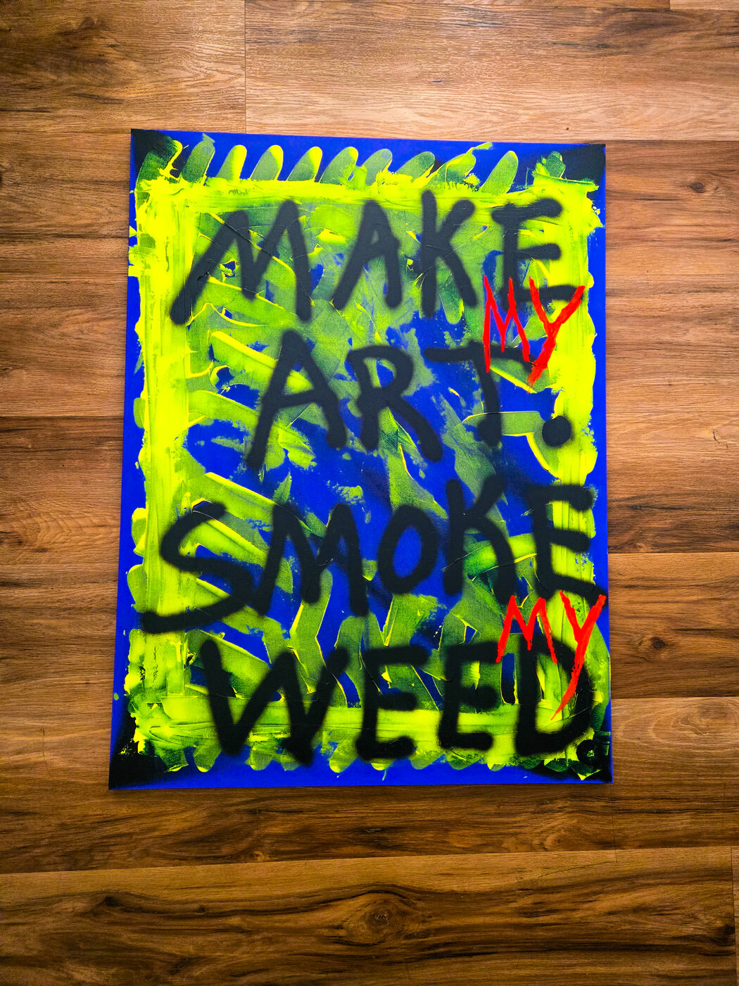 Painting reading Make my art, smoke my weed, in black and red on blue and yellow